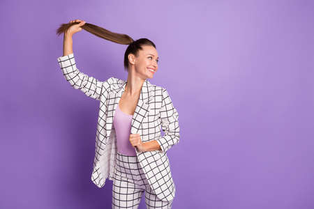Photo of attractive pretty young woman look empty space hold hair tail isolated on violet color...