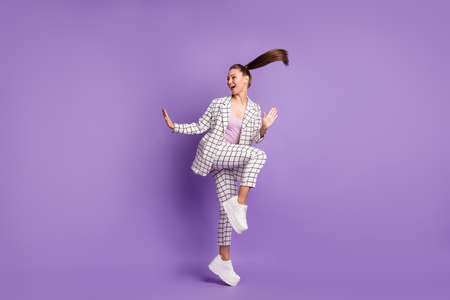 Full size photo of young funky funny smiling positive girl with flying hair dancing isolated on violet color backgroundの写真素材