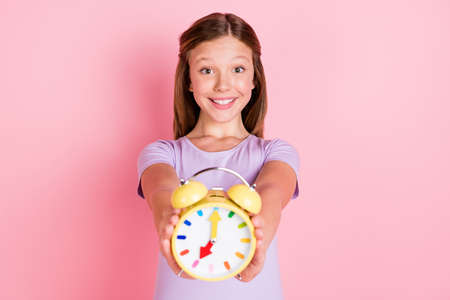 Photo of cute charming little girl hold hands clock give you time management isolated on pink color backgroundの写真素材