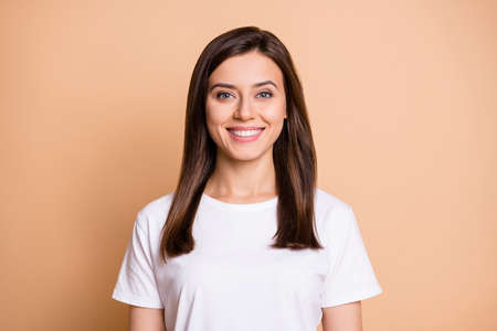 Photo portrait of pretty cute smiling girl wearing white casual tshirt isolated pastel beige color backgroundの写真素材