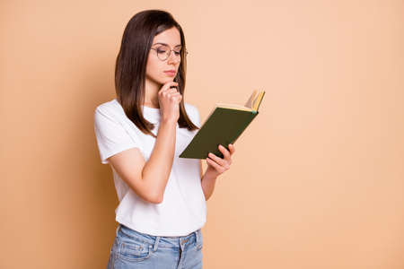 Photo portrait of girl wearing spectacles reading book information thoughtful isolated pastel beige...
