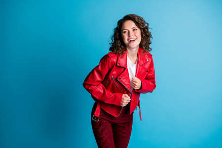 Photo of nice optimistic girl look empty space wear red jacket pants isolated on blue color...