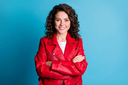 Photo of optimistic girl crossed arms wear red jacket isolated on blue color background