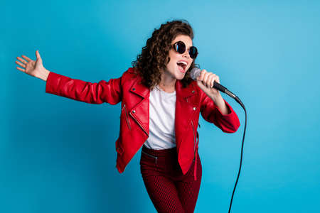 Photo of funny curly hairstyle young girl sing open mouth wear round sunglass good mood isolated on blue color backgroundの写真素材
