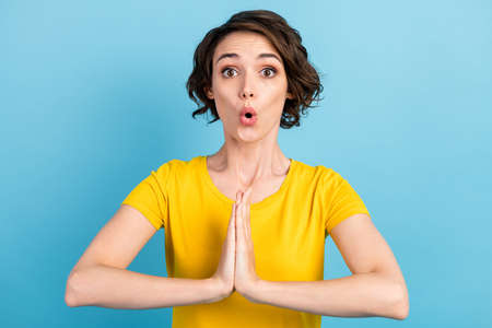 Photo of amazed young girl hold palms funny look camera wear yellow t-shirt isolated blue color...