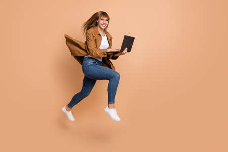 Full body profile side photo of blonde pretty woman jump run empty space hold laptop isolated on...