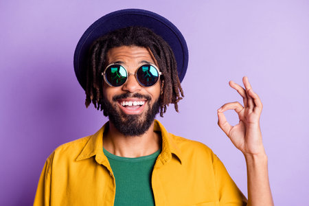 Portrait of cheerful guy front teeth gap smile fingers show okey symbol isolated on purple color...