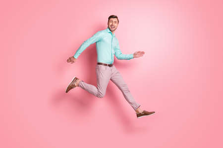 Full length profile side photo of happy cool man run jump air copyspace wear brown shoes isolated on pink color backgroundの写真素材