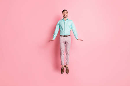 Full size photo of young happy handsome cheerful smiling businessman jumping isolated on pink color backgroundの写真素材