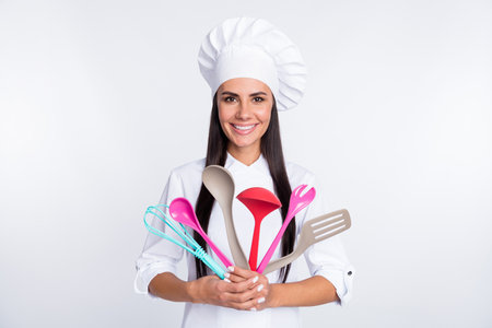 Photo of happy smiling good mood beautiful woman chef cook hold show utensils isolated on white color backgroundの写真素材