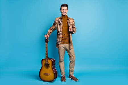 Full size photo of young happy good mood smiling positive man with acoustic guitar isolated on blue color backgroundの写真素材