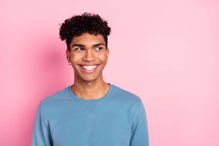 Photo of optimistic nice brunet guy look empty space wear blue sweater isolated on pastel pink color...