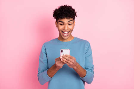 Photo portrait of young guy with piercing amazed reading news on mobile phone isolated on pastel...