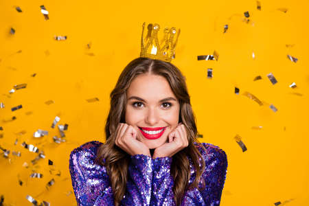 Photo portrait of overjoyed young woman cheerful wearing golden crown smiling isolated bright yellow color backgroundの写真素材