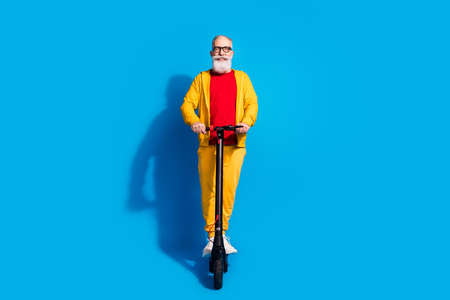 Full size portrait of positive glad person driving moped beaming smile isolated on blue color backgroundの写真素材