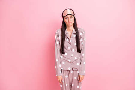 Photo of tired unhappy young woman dotted sleepwear mask early wake up isolated pastel pink color backgroundの写真素材