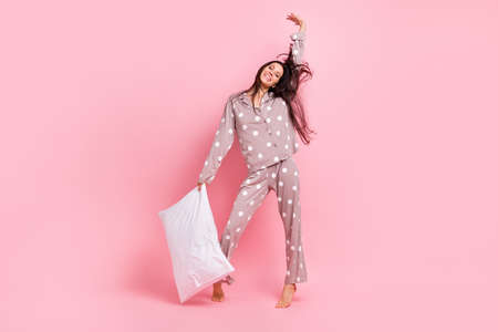 Full length photo of funky pretty young lady nightwear stretching dancing holding pillow isolated pink color backgroundの写真素材