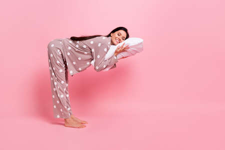 Full length photo of pretty cute young lady nightwear standing lying pillow empty space isolated pink color backgroundの写真素材