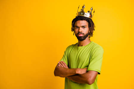 Photo of young confident serious man king wear crown crossed hands wear green t-shirt isolated over...