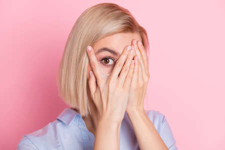 Photo of scared shocked pretty young woman hold hands face cover eye peek isolated pink color backgroundの写真素材