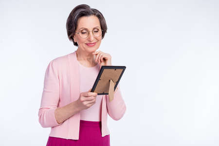 Photo of sweet thoughtful mature lady wear pink clothes glasses holding picture arm chin empty space isolated white color backgroundの写真素材