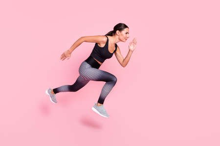 Full length profile side photo of young sporty woman go walk run fast jump cross competition...