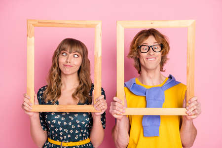 Photo of optimistic funny couple pose in frame wear colorful clothes isolated on pastel pink...