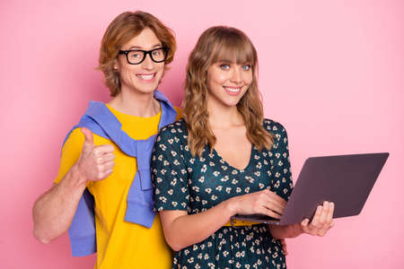 Photo of optimistic nice couple hold laptop show thumb up wear colorful clothes isolated on pastel...