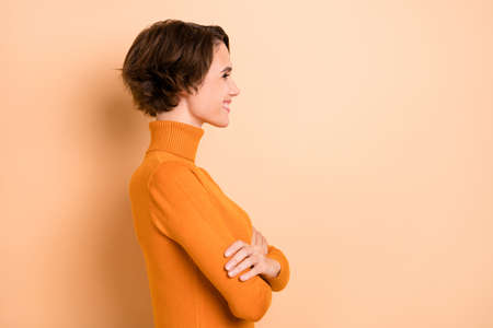 Photo of pretty charming young lady wear orange turtleneck hands arms folded isolated beige color backgroundの写真素材