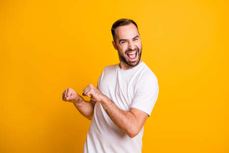 Portrait of optimistic funky guy dance wear grey t-shirt isolated on yellow color background