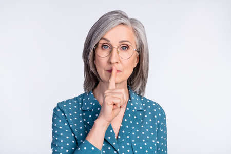 Photo of serious old woman hold finger mouth lips silence tell secret isolated on grey color backgroundの写真素材
