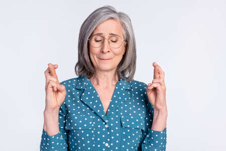 Portrait of attractive dreamy worried middle-aged lady crossed fingers asking good luck isolated over gray light pastel color backgroundの写真素材