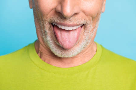 Cropped close-up portrait of attractive cheerful glad bearded grey-haired man showing tongue out isolated over bright blue color backgroundの写真素材