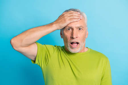 Portrait of shocked handsome man hand on forehead open mouth staring isolated on blue color backgroundの写真素材