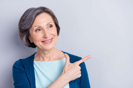 Portrait of attractive cheerful woman demonstrating copy empty blank space ad isolated over grey color backgroundの写真素材