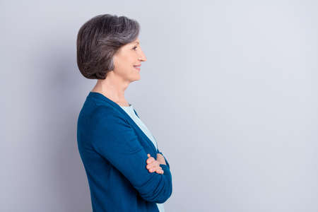 Profile side portrait of lovely cheerful gray haired woman folded arms copy empty space isolated over grey pastel color backgroundの写真素材