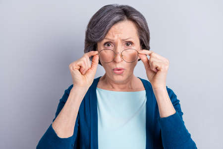 Photo of adorable shocked mature lady dressed blue outfit arms spectacles big eyes isolated grey color backgroundの写真素材