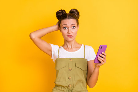 Portrait of attractive puzzled girl using device browsing fake news bad comment isolated over bright...