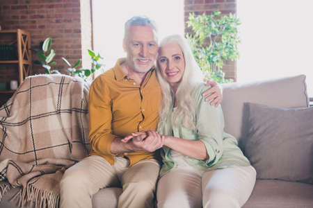 Photo of old charming pretty grandmother grandfather sitting sofa embracing indoors flat home house