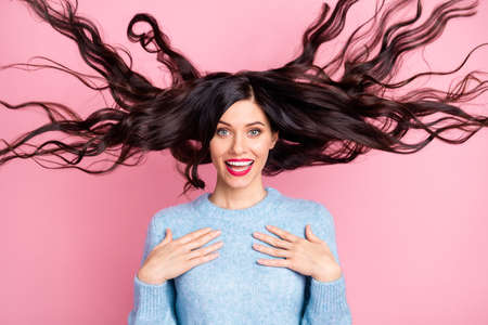 Photo of charming lady look camera wind blow wavy hairdo palms chest wear blue sweater isolated pink...