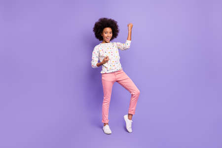 Full size photo of lucky pretty dark skin girl raise fists win wear pink trousers isolated on violet color backgroundの写真素材