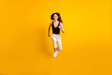 Full length body size photo of woman jumping running fast on sale smiling isolated bright yellow color backgroundの写真素材