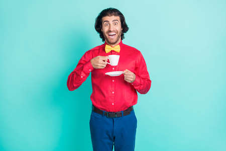 Photo of young funky funny smiling excited gentleman drinking tea having break relaxing isolated on teal color backgroundの写真素材