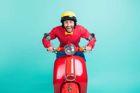 Photo of optimistic brunette guy ride bike wear red shirt helmet isolated on teal color backgroundの写真素材