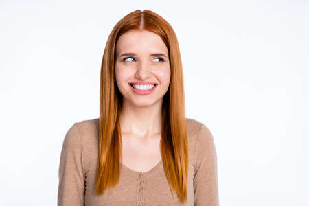 Photo of excited funny redhair woman beige shirt smiling looking empty space isolated white color backgroundの写真素材