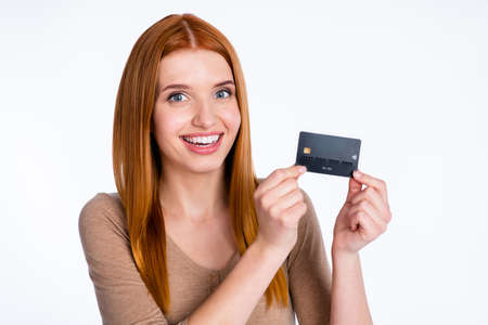 Photo of pretty sweet redhair woman beige shirt holding arms bank card smiling isolated white color...