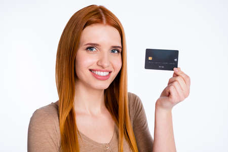 Photo of adorable cute ginger lady wear beige shirt smiling holding credit card isolated white color backgroundの写真素材