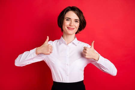 Photo portrait of happy business woman wearing white shirt showing like sign isolated vivid red color backgroundの写真素材