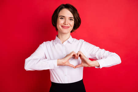 Photo portrait of happy business woman showing heart shaped sign hands isolated vivid red color backgroundの写真素材