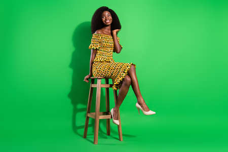 Full body portrait of charming dark skin lady arm touch hair look empty space isolated on green color backgroundの写真素材